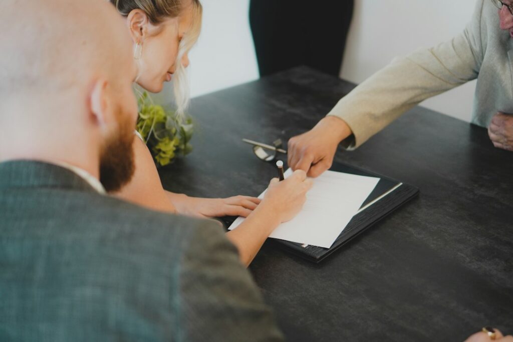 Couple reviewing and signing documents at a desk after a home sale falls through in 2026