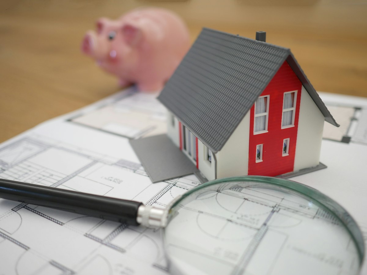 Small model house beside a magnifying glass representing a closer look at real estate investing returns in 2026